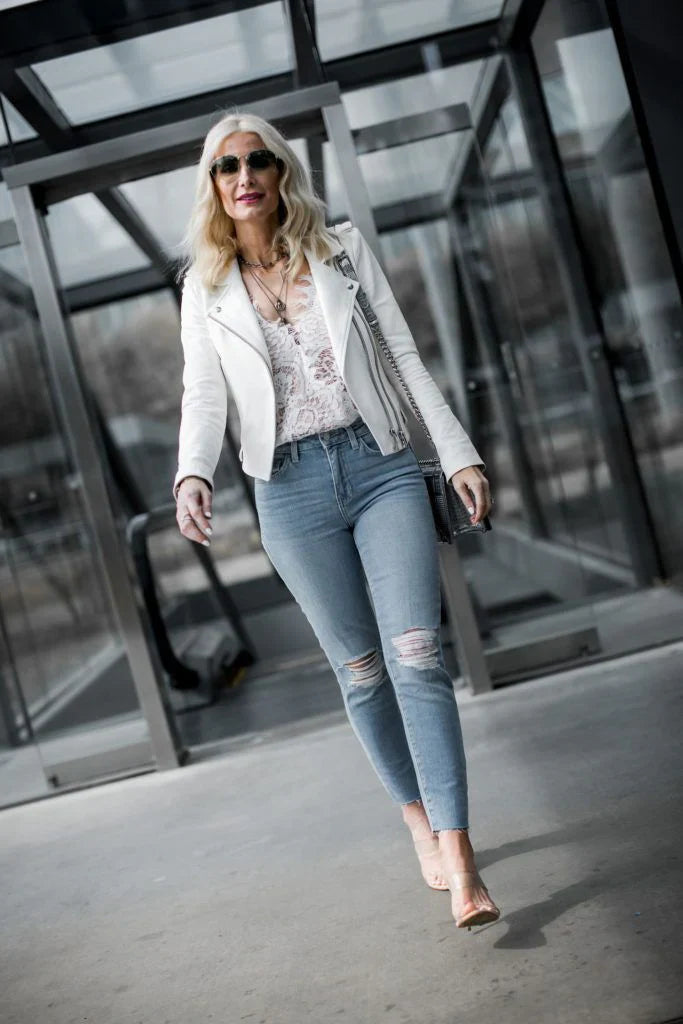 Stylish woman wearing a white leather jacket paired with jeans and heels for a chic look.