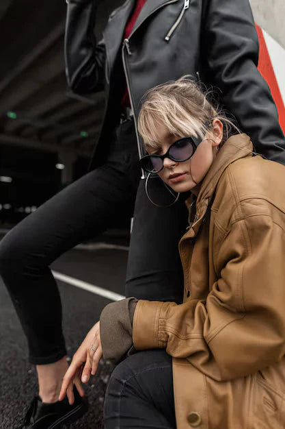 Woman wearing a vintage brown leather jacket styled with jeans and retro sunglasses
