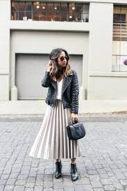 Woman wearing a black leather jacket paired with a pleated midi skirt and ankle boots for a chic feminine look.