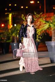 Woman wearing a pastel lightweight leather jacket over a floral spring dress in a blooming park setting.
