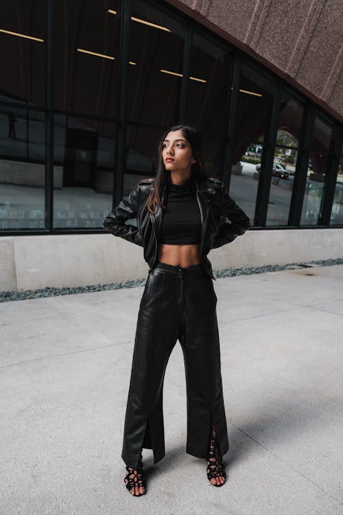 A stylish woman wearing an oversized black leather jacket with high-waist jeans and a crop top, channeling 90s fashion.